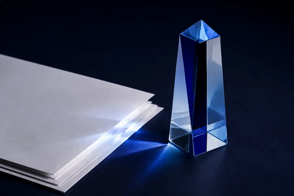 Blue glass refracting light beside a stack of paper